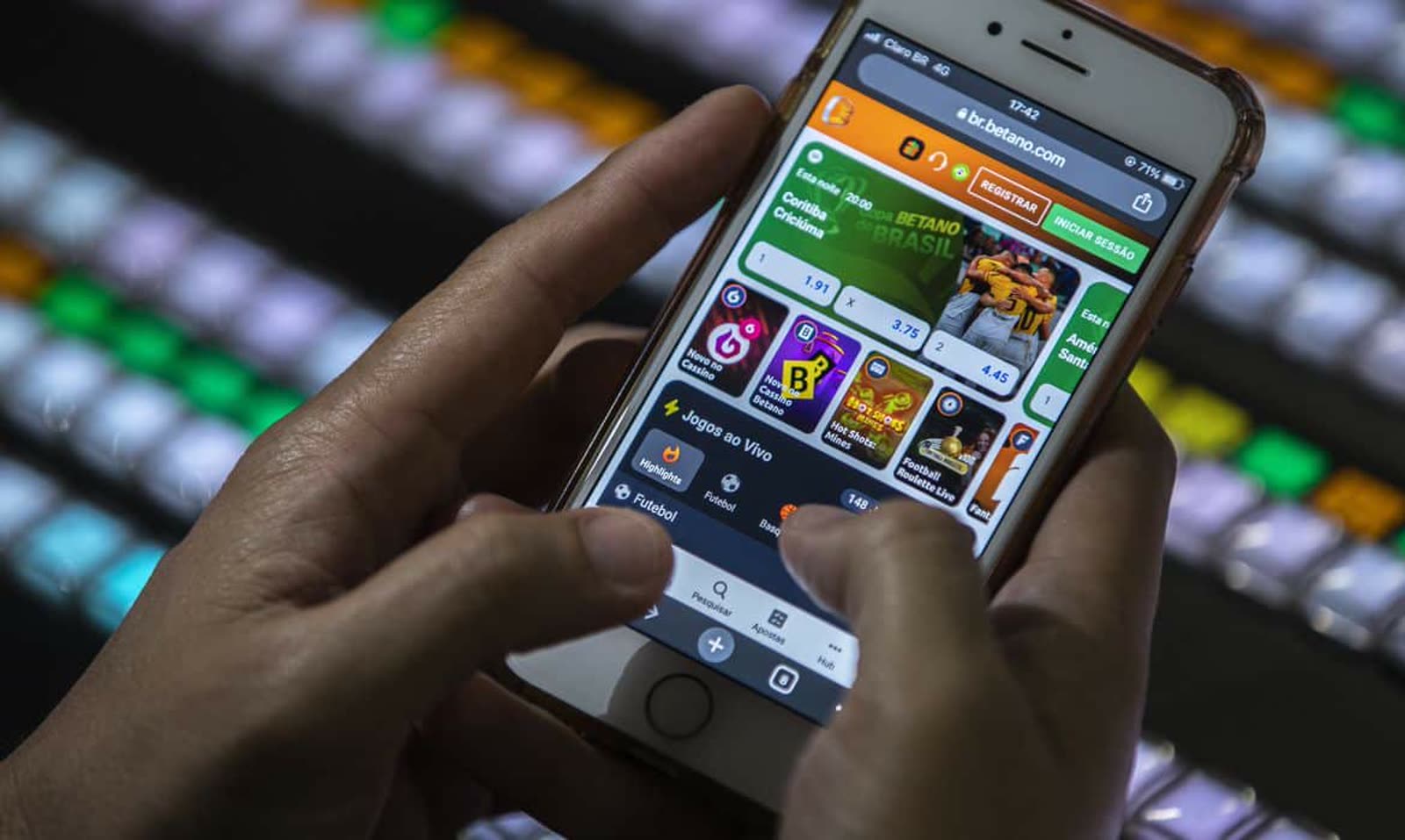 Mãos segurando um celular com aplicativo de apostas aberto